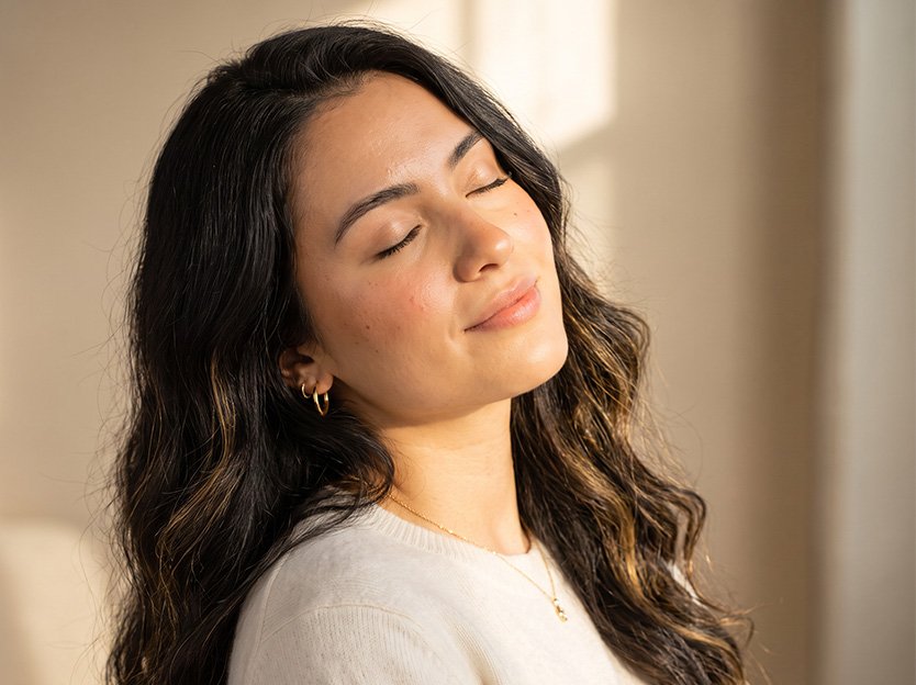 Woman with softly styled wavy hair and radiant skin in warm sunlight